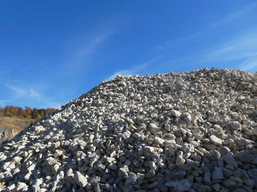 Bschor GmbH: Ein großer Haufen Schroppen liegt im Freien unter einem klaren blauen Himmel, und im Hintergrund sind einige Bäume zu sehen.