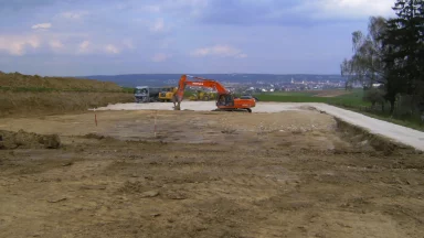 Bschor GmbH: Eine Baustelle mit einem großen Bagger und Lastwagen.